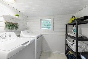 A laundry room with a washing machine, dryer, and shelves with laundry baskets. - St. Augustine | Hot Tub | Parking | Walk Downtown (St. Augustine)