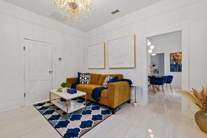 A modern living room with a sofa, coffee table, and artwork on the wall. - St. Augustine | Hot Tub | Parking | Walk Downtown (St. Augustine)
