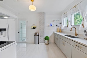 A modern kitchen with white cabinetry, a stainless steel sink, and a hanging light fixture. - St. Augustine | Hot Tub | Parking | Walk Downtown (St. Augustine)