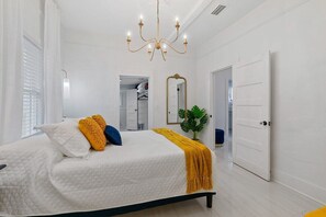 A bedroom with a bed, a chandelier, a mirror, and a door. - St. Augustine | Hot Tub | Parking | Walk Downtown (St. Augustine)