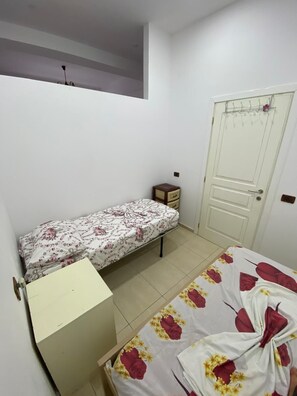 A bedroom with a bed, a small bedside table, a wardrobe, and a door with a hanging rack. - Aura Holiday Home - Golem (Golem)