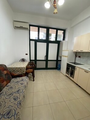 A compact living space with a kitchenette, a dining area, and a sofa. - Aura Holiday Home - Golem (Golem)
