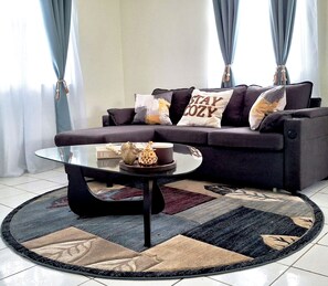 A living room with a sofa, a coffee table, and a rug. - The Brontie Cottage (Christ Church Nichola Town Parish)