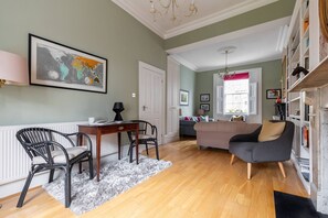 A well-lit living room with a sofa, a dining table with chairs, and a bookshelf. - Remington Street - Four Bedroom Apartment, Sleeps 6 (London)