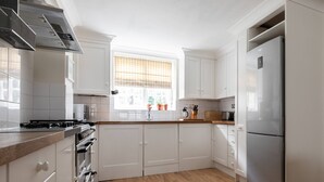 A modern kitchen with white cabinetry, a stainless steel refrigerator, and a wooden countertop. - Remington Street - Four Bedroom Apartment, Sleeps 6 (London)