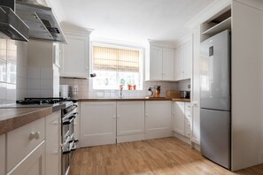 Eine moderne Küche mit weißen Schränken, einem Edelstahl-Kühlschrank und einer Holz Arbeitsplatte.