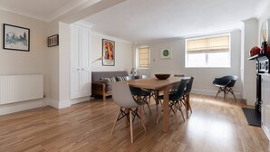 A modern kitchen with a dining area, white cabinetry, and a view of the cityscape. - Remington Street - Four Bedroom Apartment, Sleeps 6 (London)