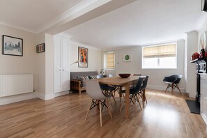 A modern kitchen with a dining area, white cabinetry, and a view of the cityscape.