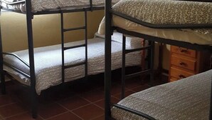 Una cama litera con un colchón estampado, un aparador de madera y un piso de baldosas.