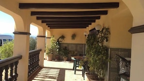An outdoor balcony with a wooden pergola, potted plants, and a view of a vehicle in the background. - Casa La Torre Arriate by Ruralidays (Málaga)