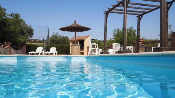Una piscina con agua cristalina, rodeada de sillones de descanso y una estructura de pérgola.