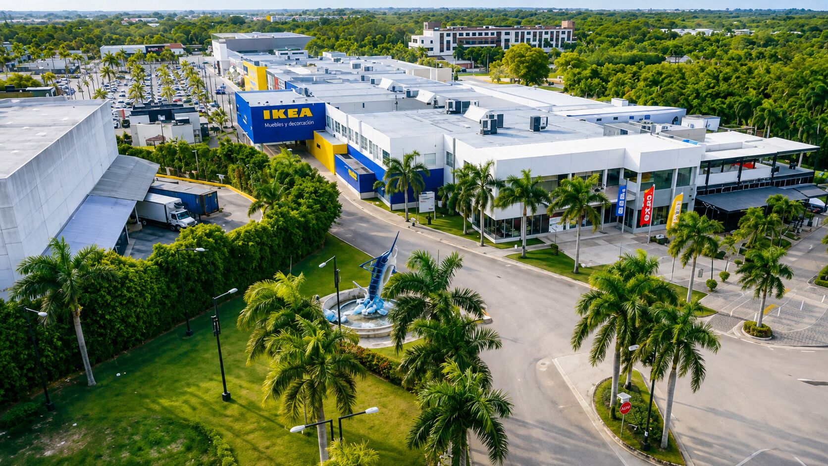 Un immeuble commercial arborant une enseigne IKEA bien visible, entouré de palmiers et d’un parking.