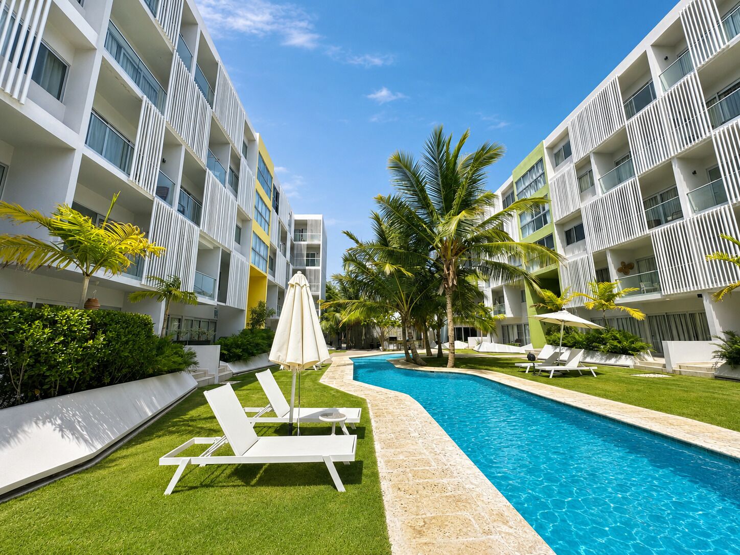 Ein modernes Hotel mit Swimmingpool, Liegestühlen und Palmen.