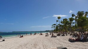 A beach with palm trees, sun loungers, and people. - Poolside condo Downtown Punta Cana &$& (Punta Cana)