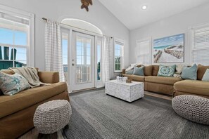A living room with two sofas, a coffee table, and a view of the outdoors through large windows. - Gulf-View Retreat: Walk to Beach & Pier Park (Panama City Beach)