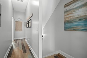 A hallway with a wooden floor, white walls, and a painting. - Gulf-View Retreat: Walk to Beach & Pier Park (Panama City Beach)