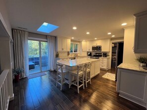 A modern kitchen with a central island, white cabinetry, and a skylight. - Ward Lake Retreat - Lake View, Neighborhood Dock & Sports Court (Olympia)