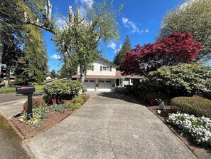 A residential property with a driveway leading to a garage, surrounded by well-maintained landscaping and mature trees. - Ward Lake Retreat - Lake View, Neighborhood Dock & Sports Court (Olympia)