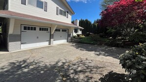 A two-story house with a garage, a driveway, and a garden with red foliage. - Ward Lake Retreat - Lake View, Neighborhood Dock & Sports Court (Olympia)