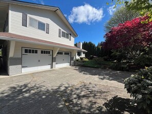A two-story house with a garage, a driveway, and a garden with red foliage. - Ward Lake Retreat - Lake View, Neighborhood Dock & Sports Court (Olympia)