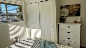 A bedroom with a bed, a white wardrobe, a window with blinds, and a wall decoration. - Ward Lake Retreat - Lake View, Neighborhood Dock & Sports Court (Olympia)