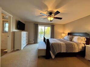 A bedroom with a bed, a nightstand, a dresser, a ceiling fan, and a TV. - Ward Lake Retreat - Lake View, Neighborhood Dock & Sports Court (Olympia)