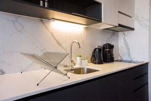 A modern kitchen with a marble countertop, a stainless steel sink, a kettle, and a kettle holder. - Apartment Nearby Metro with Pool (Ñuñoa)