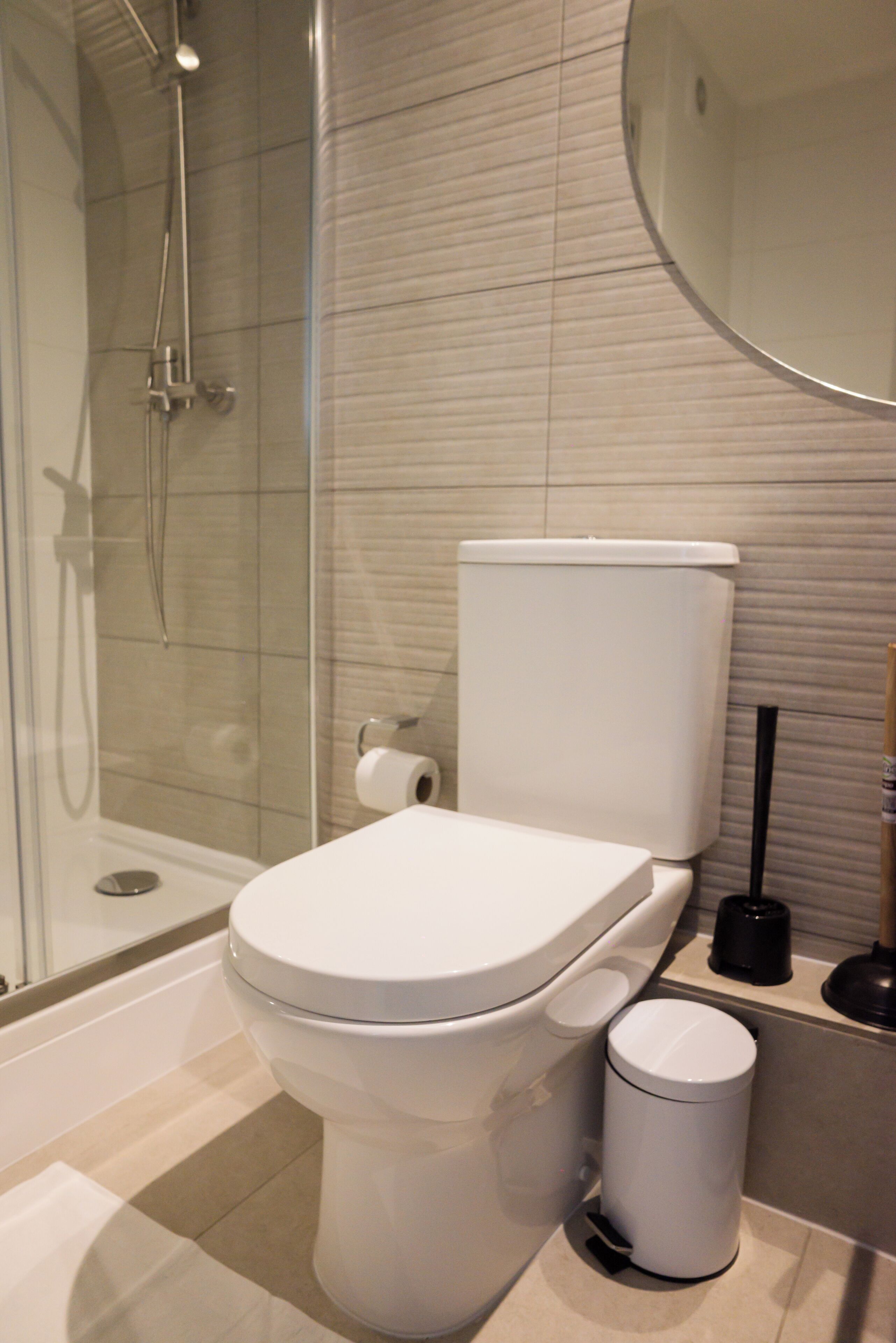 A modern bathroom with a toilet, a bidet, a shower, and a toilet paper holder.