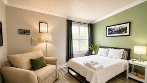 A hotel room with a bed, a sofa, a lamp, a picture on the wall, and a window with curtains.