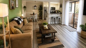 A living room with a sofa, coffee table, and a dining area with chairs and a table.