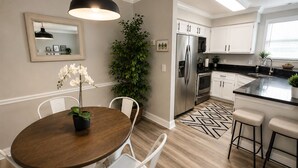 A modern kitchen with white cabinets, a stainless steel refrigerator, and a black countertop.