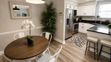 A modern kitchen with white cabinets, a stainless steel refrigerator, and a black countertop.