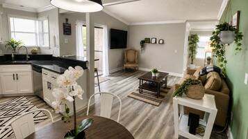 A modern kitchen with white cabinets, a black countertop, and a dining area with a round table and chairs.