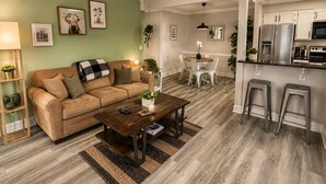 A modern living room with a sofa, coffee table, and a dining area with chairs.