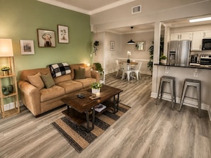 A modern living room with a sofa, coffee table, and a dining area with chairs.