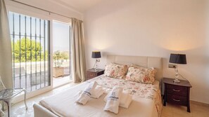 Ein Hotelzimmer mit einem Bett, zwei Nachttischen, einem Sessel und einem Balkon mit Blick.