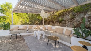 Ein Sitzbereich im Freien mit einer Pergola, gepolsterten Sofas und einem Couchtisch.