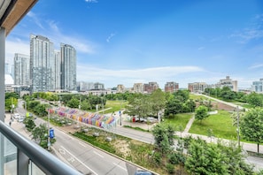 Paesaggio urbano con grattacieli, un'area verde e una strada con veicoli.