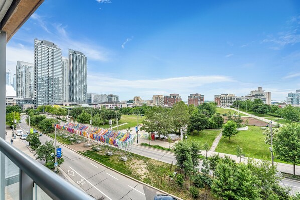 Un paisaje urbano con edificios altos, un parque con césped y una calle con vehículos.