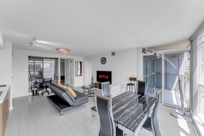 Una sala de estar moderna con un sofá, una mesa de comedor, un televisor y un ventanal grande.