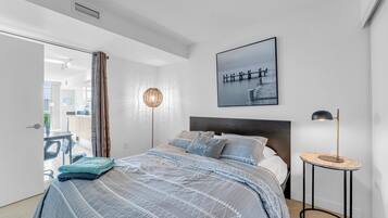 A modern bedroom with a bed, a bedside table, a lamp, and a picture on the wall.