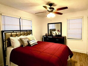 A bedroom with a bed, a nightstand, a mirror, and a ceiling fan. - House of Gems Relax & Unwind Beautiful Atlanta Home for Families & Groups (Atlanta)