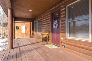 A wooden cabin with a porch, a red door, and a wreath.