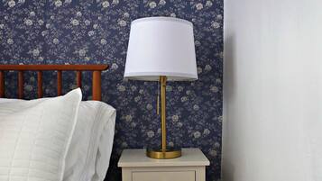 Una camera da letto con un letto, un comodino con una lampada e carta da parati floreale.