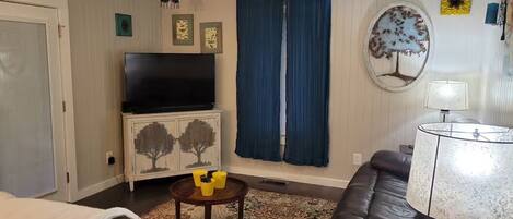A living room with a ceiling fan, a television on a cabinet, a sofa, a coffee table, and a lamp.