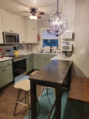 A kitchen with a central island, a ceiling fan, and a hanging light fixture. - Charming cottage in the mountains of NE Georgia, five minutes from Clayton, GA. (Clayton)