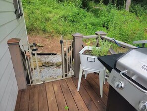 A wooden deck with a grill and a planter box. - Charming cottage in the mountains of NE Georgia, five minutes from Clayton, GA. (Clayton)