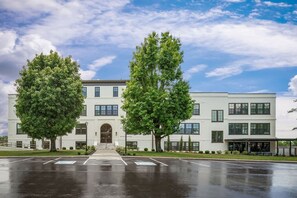 A two-story building with a central entrance, surrounded by trees and a parking lot.