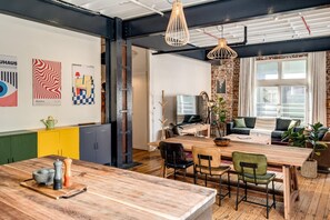 A modern interior with a wooden dining table, chairs, a kitchen area, and a seating area with a sofa and a coffee table. - Central City 2bed With Mountain Views Skywood Loft (Cape Town)
