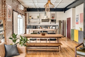Eine moderne Küche mit Holztisch und Bank, einer Hängeleuchte und einer Ziegelwand.